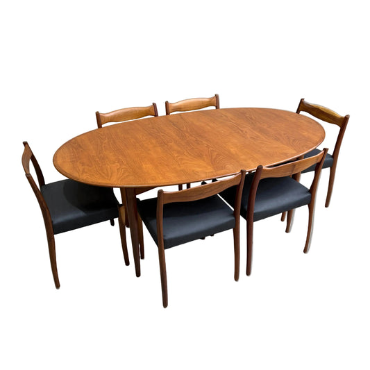 A fully restored mid-century Parker 91 oval teak dining suite with six Fler 64 blackwood chairs (Rediscover), all set against a plain gray background.