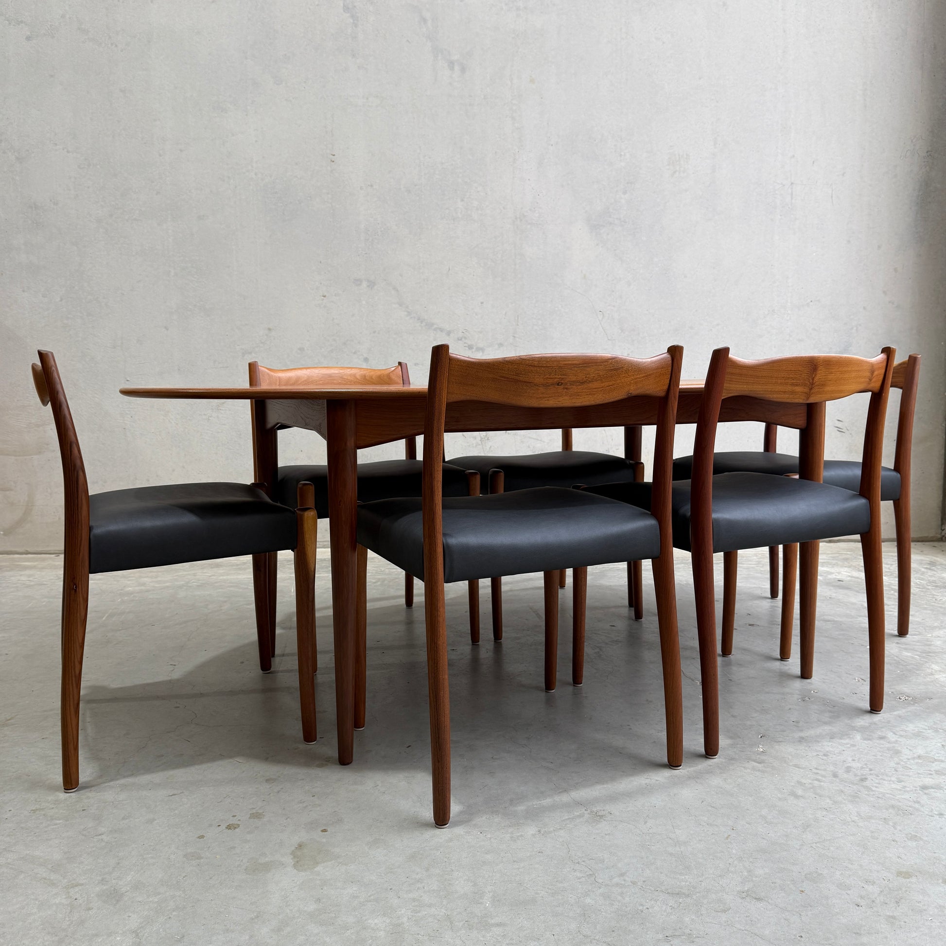 The Fully Restored Mid-Century Parker 91 Oval Teak Dining Suite with 6 Fler 64 Blackwood Chairs (Rediscover) offers timeless Australian elegance, perfect against a minimalist backdrop for sophisticated dining.
