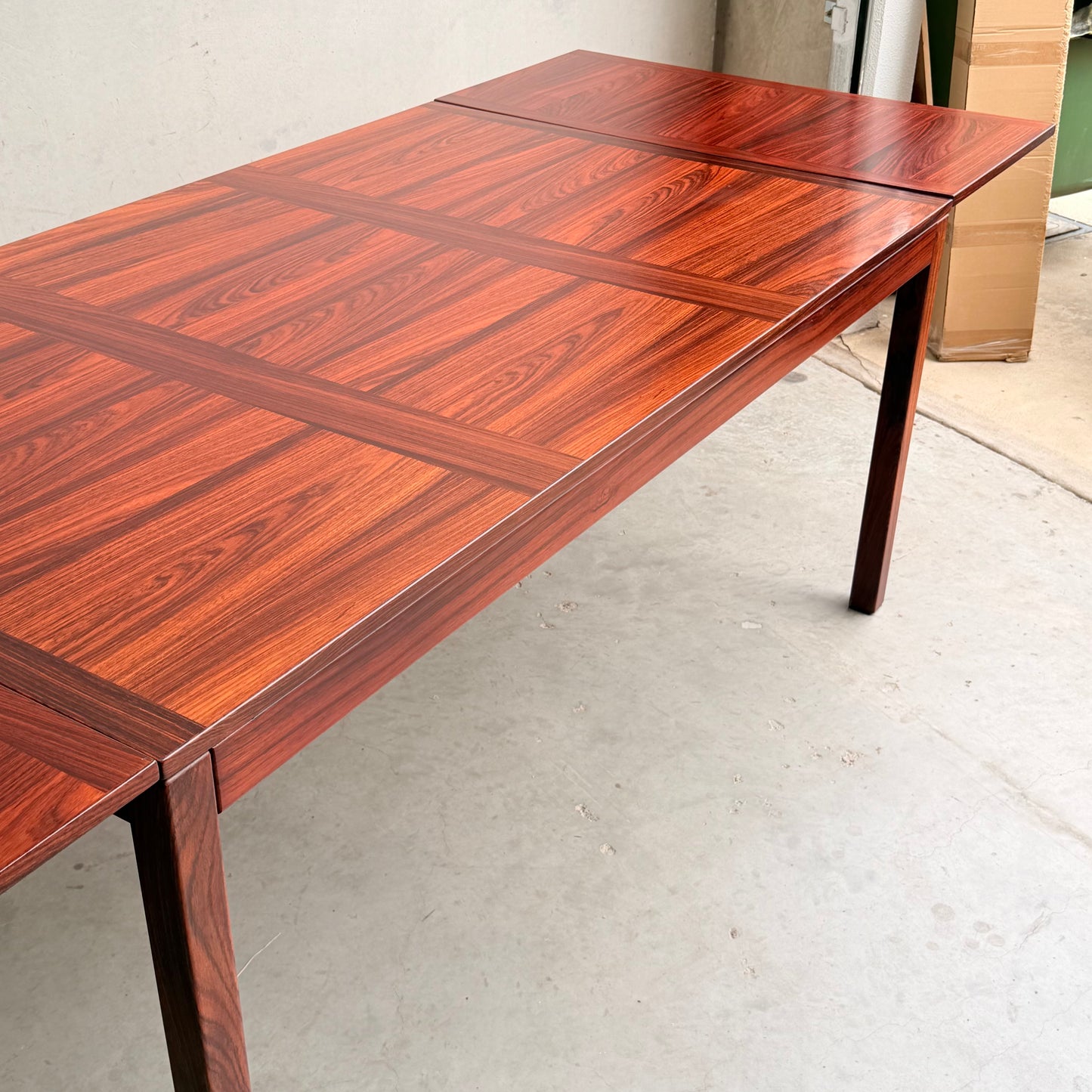 A 1970s Danish Modern Rosewood Dropleaf Dining Table by Vejle Stole og Mobelfabrik (Model 166, 1975), featuring a glossy, patterned surface and straight legs—a classic example of mid-century Danish design in a minimal indoor space.
