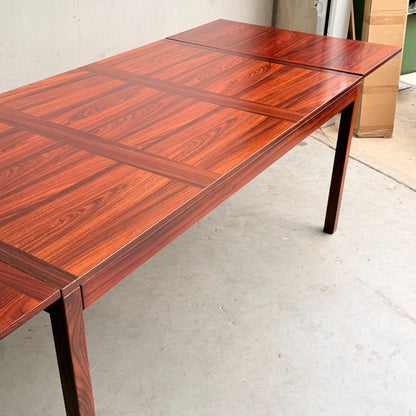 A 1970s Danish Modern Rosewood Dropleaf Dining Table by Vejle Stole og Mobelfabrik (Model 166, 1975), featuring a glossy, patterned surface and straight legs—a classic example of mid-century Danish design in a minimal indoor space.