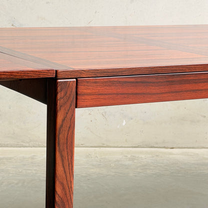 Close-up of a 1970s Danish Modern Rosewood Dropleaf Dining Table by Vejle Stole og Mobelfabrik (Model 166, 1975), showing rich reddish-brown grain and a smooth, glossy surface against a light wall and concrete floor.
