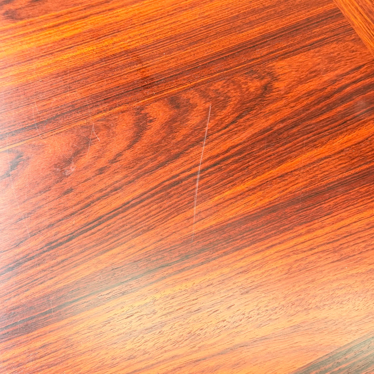 Close-up of a polished, reddish-brown rosewood surface from the 1970s Danish Modern Rosewood Dropleaf Dining Table (Model 166, 1975) by Vejle Stole og Mobelfabrik, highlighting its visible grain and classic mid-century glossy finish.