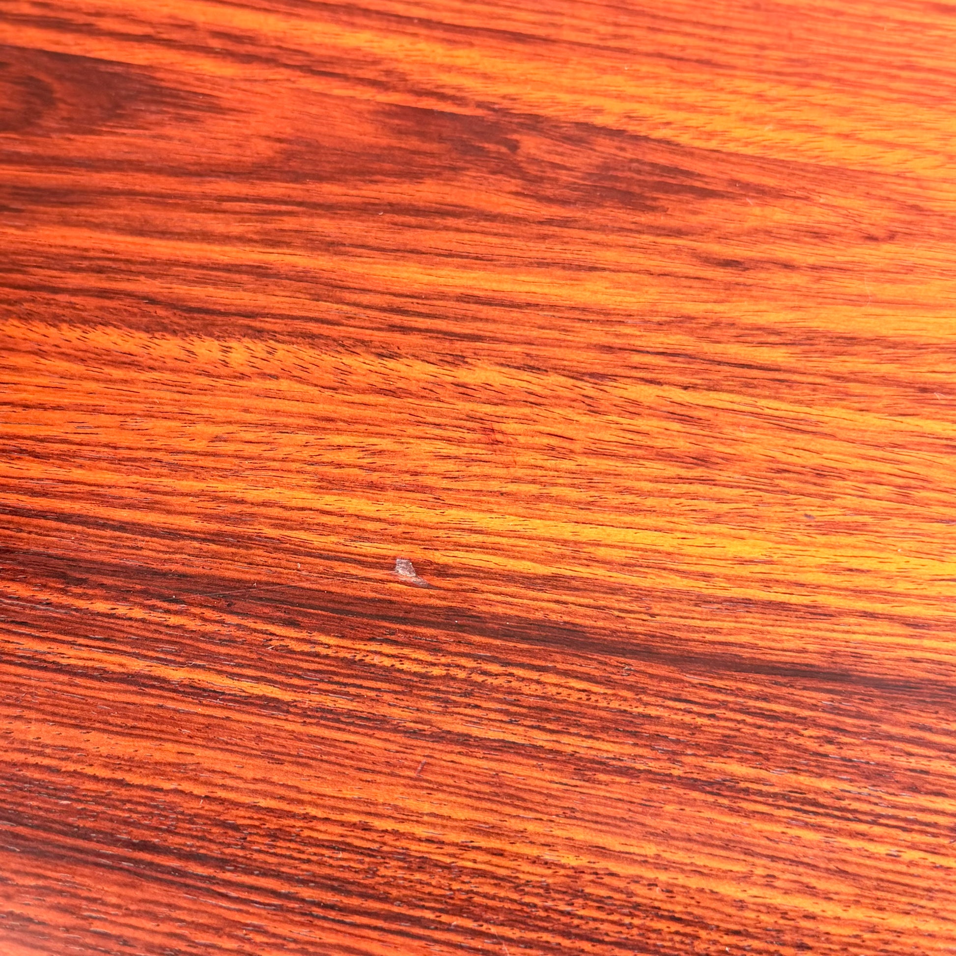 A close-up of a 1970s Danish Modern Rosewood Dropleaf Dining Table by Vejle Stole og Mobelfabrik (Model 166, 1975) shows orange and brown grain with a small chip near the center, indicating minor wood damage.