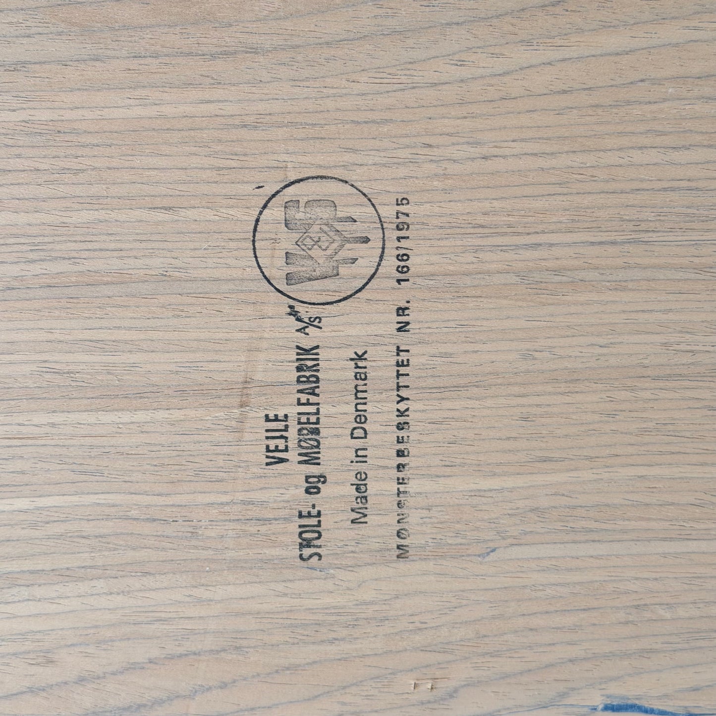 Close-up of a wooden surface stamped with "Vejle Stole og Mobelfabrik, Made in Denmark"—the hallmark found on this 1970s Danish Modern Rosewood Dropleaf Dining Table (Model 166, 1975).