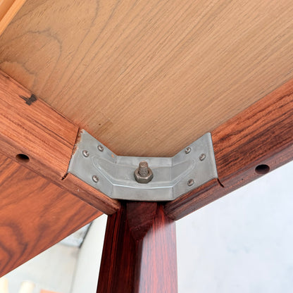 Close-up view of the underside of a 1970s Danish Modern Rosewood Dropleaf Dining Table by Vejle Stole og Mobelfabrik (Model 166, 1975), showing a metal bracket with screws and a bolt securing the legs to the richly finished rosewood tabletop.