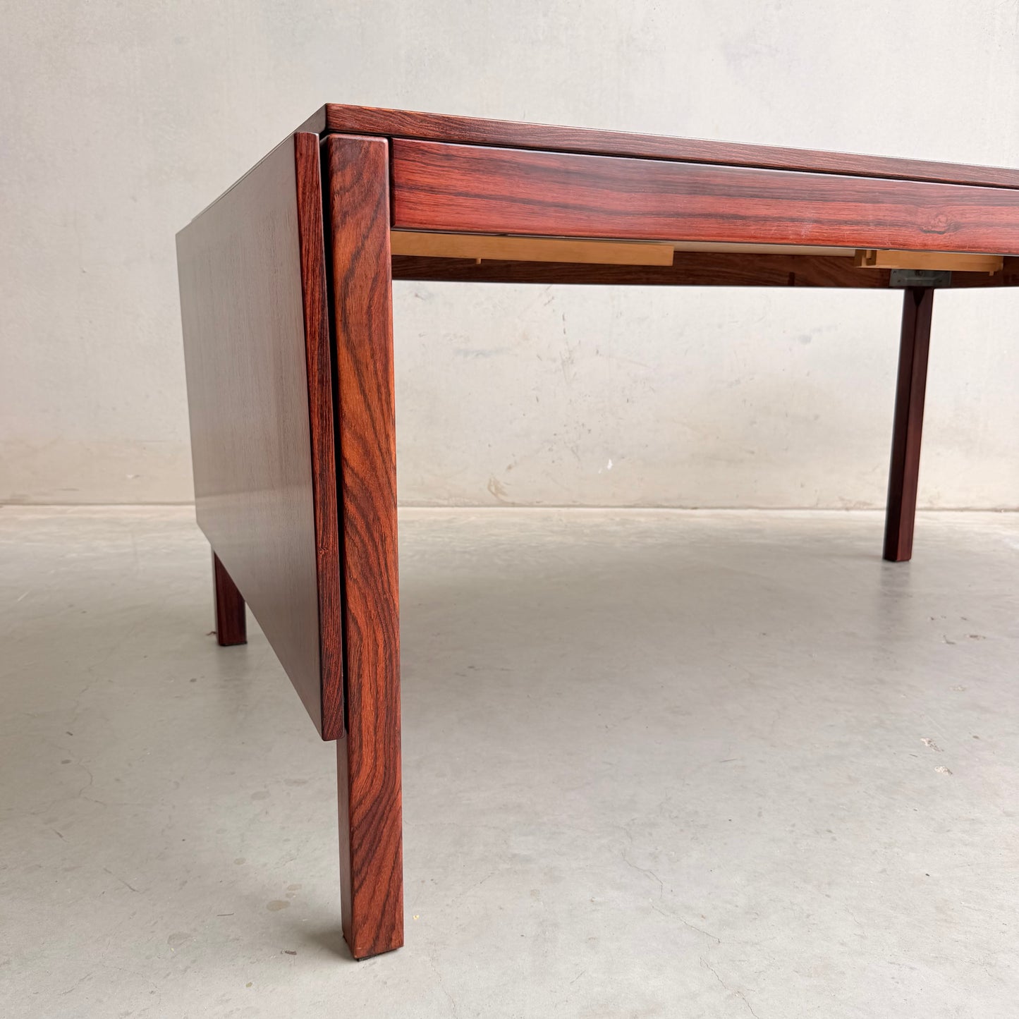 A close-up of a 1970s Danish Modern Rosewood Dropleaf Dining Table by Vejle Stole og Mobelfabrik (Model 166, 1975) highlights its clean lines, rich reddish-brown wood grain, and iconic rectangular leg design.