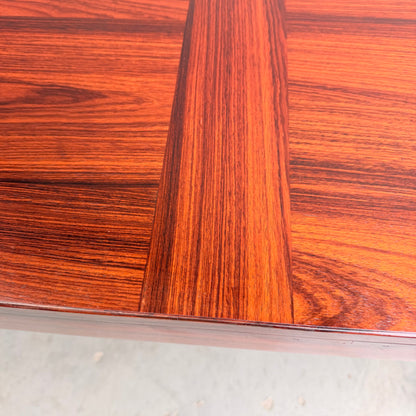 Close-up of a 1970s Danish Modern Rosewood Dropleaf Dining Table by Vejle Stole og Mobelfabrik (Model 166, 1975), featuring intersecting reddish-brown grain panels and a reflective surface that highlights its elegant mid-century design.