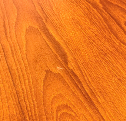 Close-up of a warm, orange-brown wooden surface with visible grain patterns—perfect for pairing with the Fully Restored Mid-Century Parker 91 Oval Teak Dining Suite and 6 Fler 64 Blackwood Chairs (Rediscover)—showing a small scratch near the center.