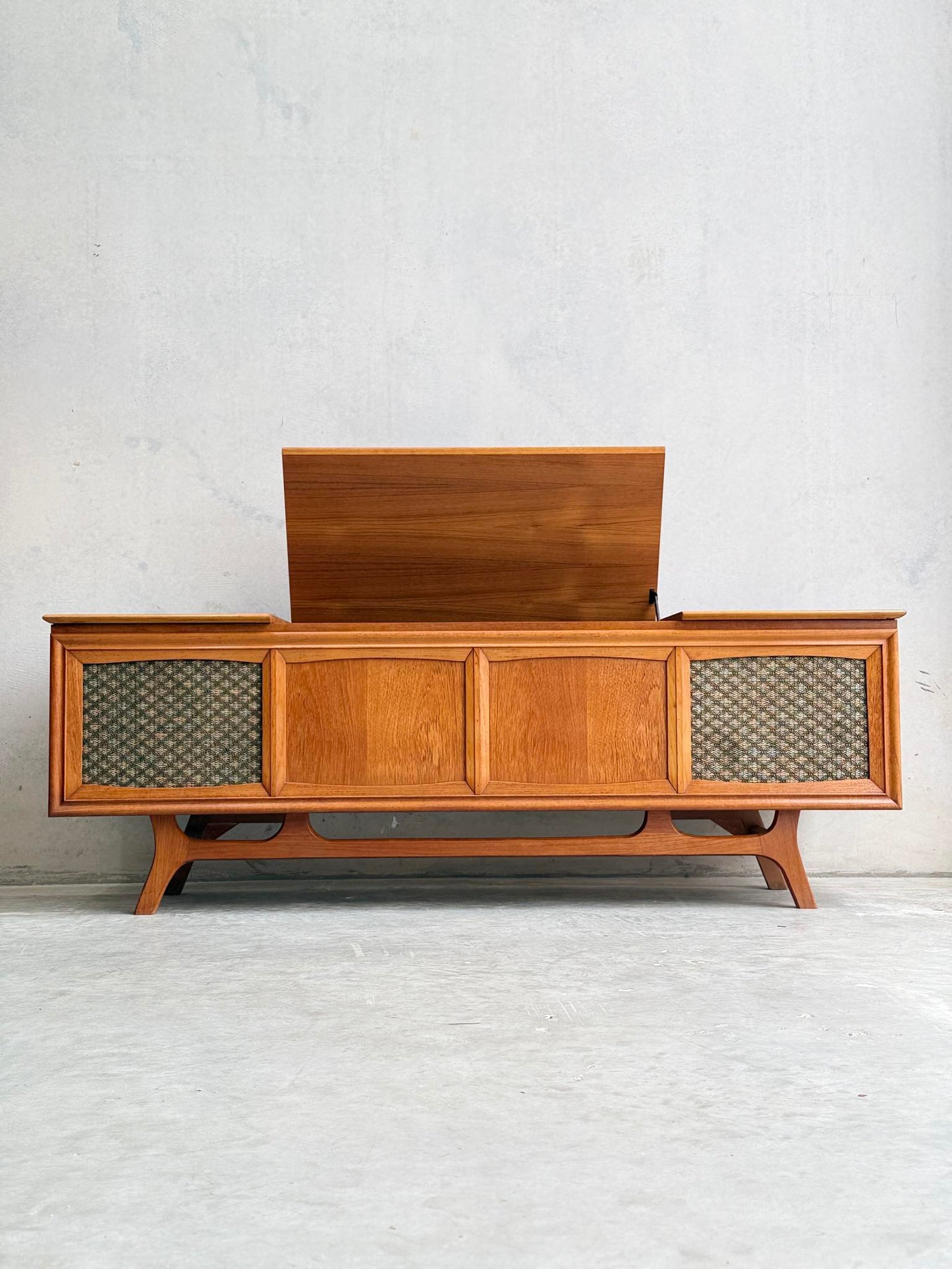 The General Electric Credenza - Spacemaker 250, a fully converted teak TV/entertainment console, features a lift-up lid and woven speaker grilles, and is set against a plain light gray wall.