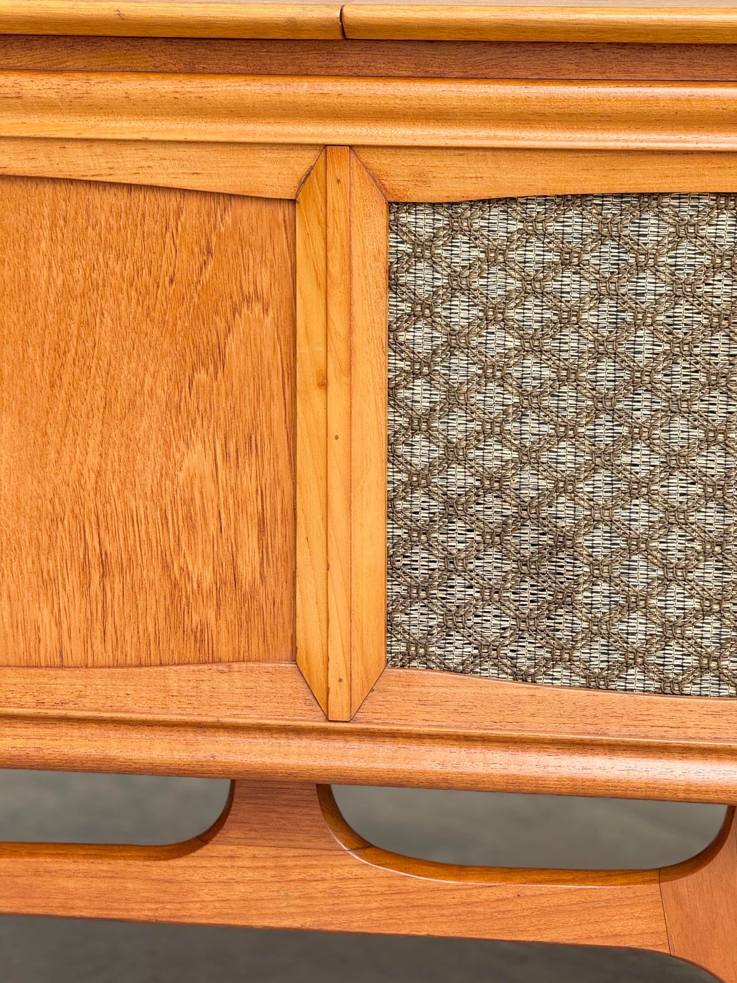 Close-up of the General Electric Credenza - Spacemaker 250, a fully converted teak TV/entertainment console with book-matched grain, textured fabric panel, and geometric lines inspired by classic 1960s mid-century modern design.
