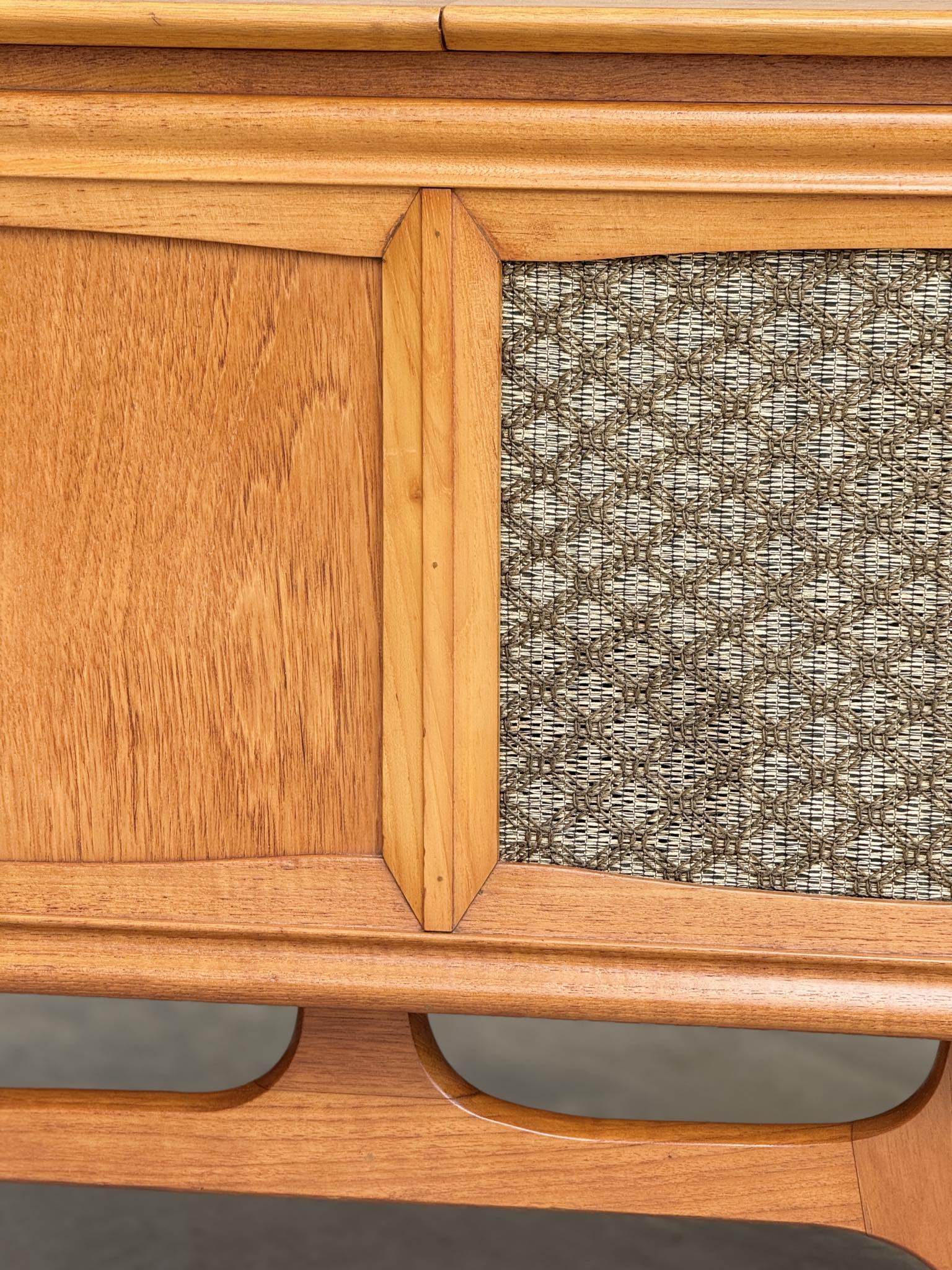 Close-up of the General Electric Credenza - Spacemaker 250, a fully converted teak TV/entertainment console with book-matched grain, textured fabric panel, and geometric lines inspired by classic 1960s mid-century modern design.