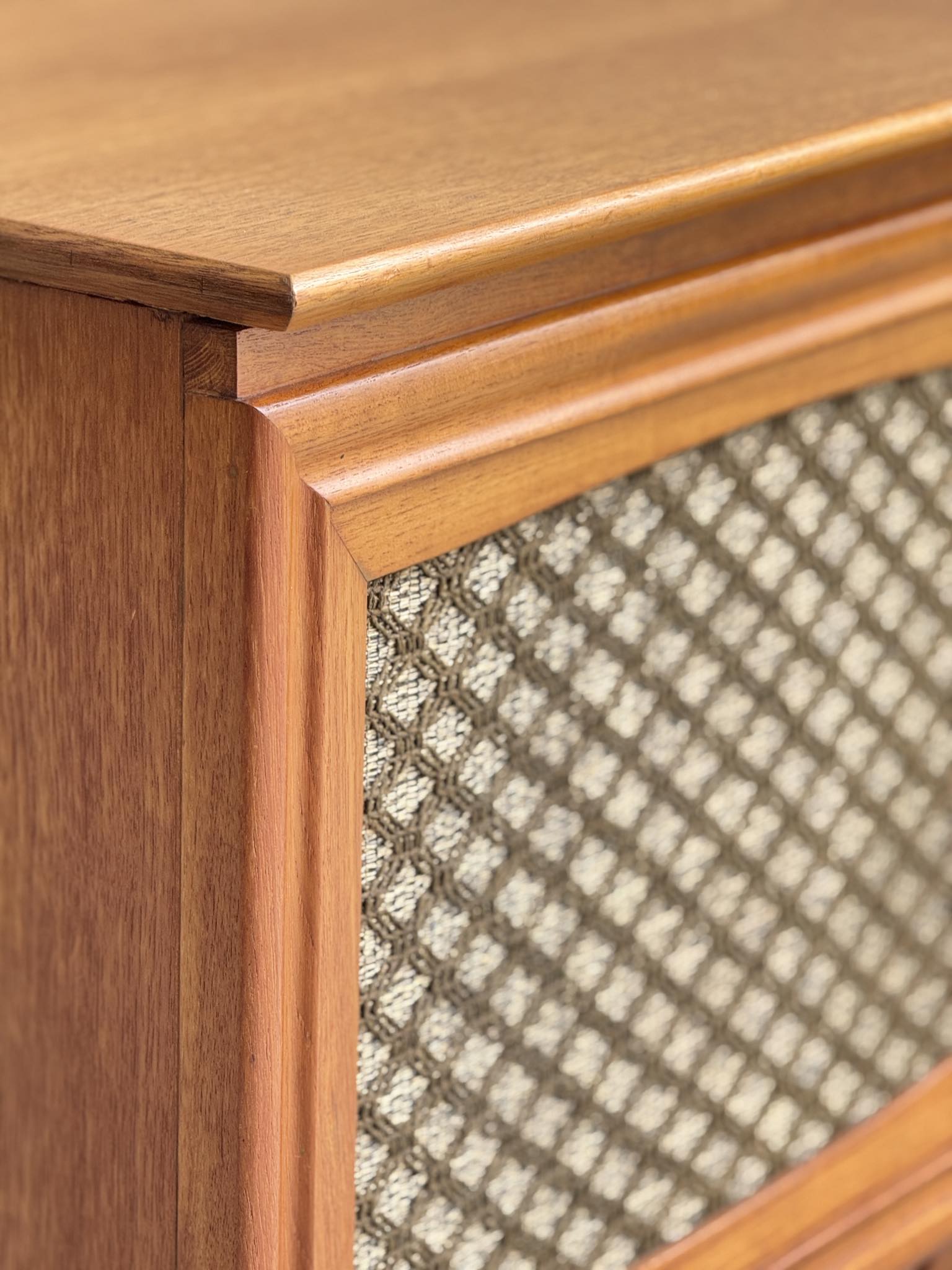 Close-up of the General Electric Credenza - Spacemaker 250, a fully converted teak TV/entertainment console featuring a book-matched cabinet corner and decorative diamond-patterned fabric grille, all in a warm, polished mid-century modern finish.