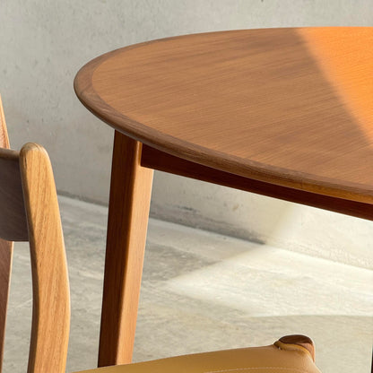 A close-up of the Fully Restored Noblett Nordic Round MCM Table (Rediscover) shows sunlight casting soft shadows on a light floor and wall, highlighting its lacquer finish and creating a warm, minimalist vibe.