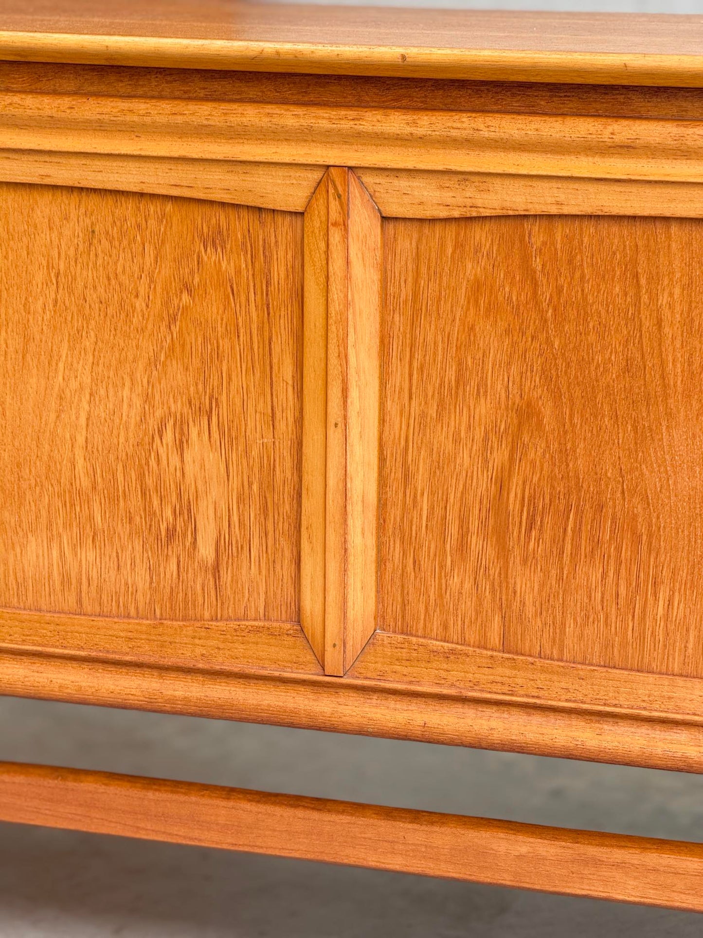 Close-up of the General Electric Credenza - Spacemaker 250, a fully converted teak TV/entertainment console, highlighting its warm honey-toned wood grain and smooth finish with a mid-century modern decorative panel design.