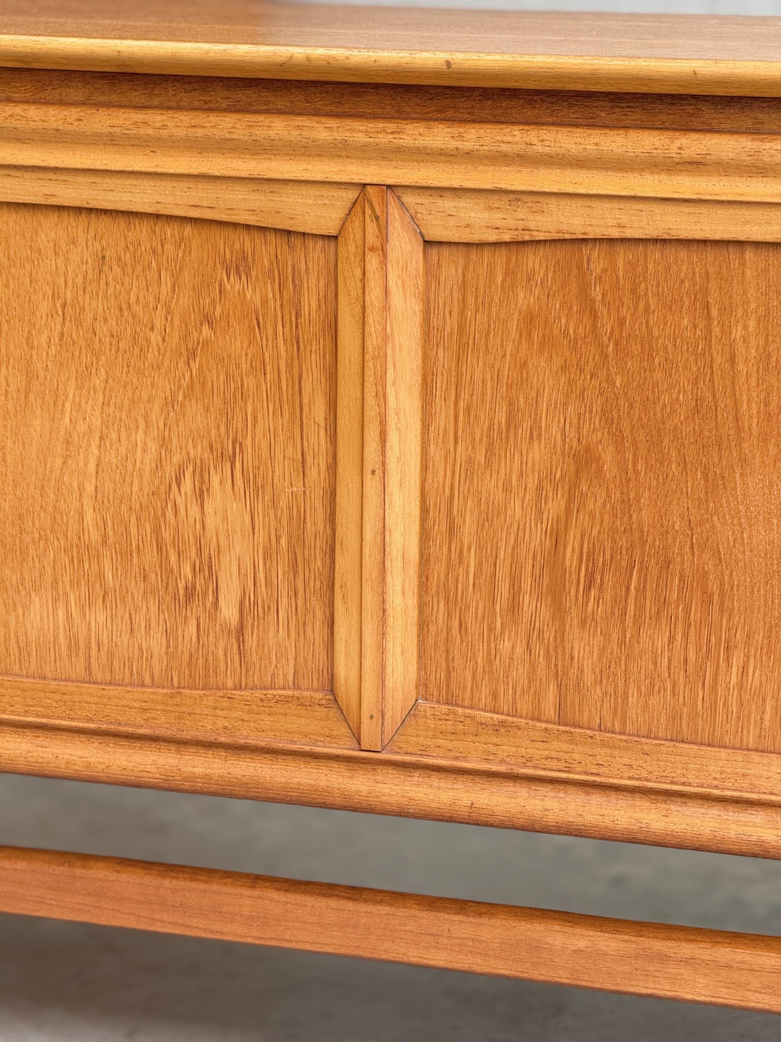 Close-up of the General Electric Credenza - Spacemaker 250, a fully converted teak TV/entertainment console, highlighting its warm honey-toned wood grain and smooth finish with a mid-century modern decorative panel design.